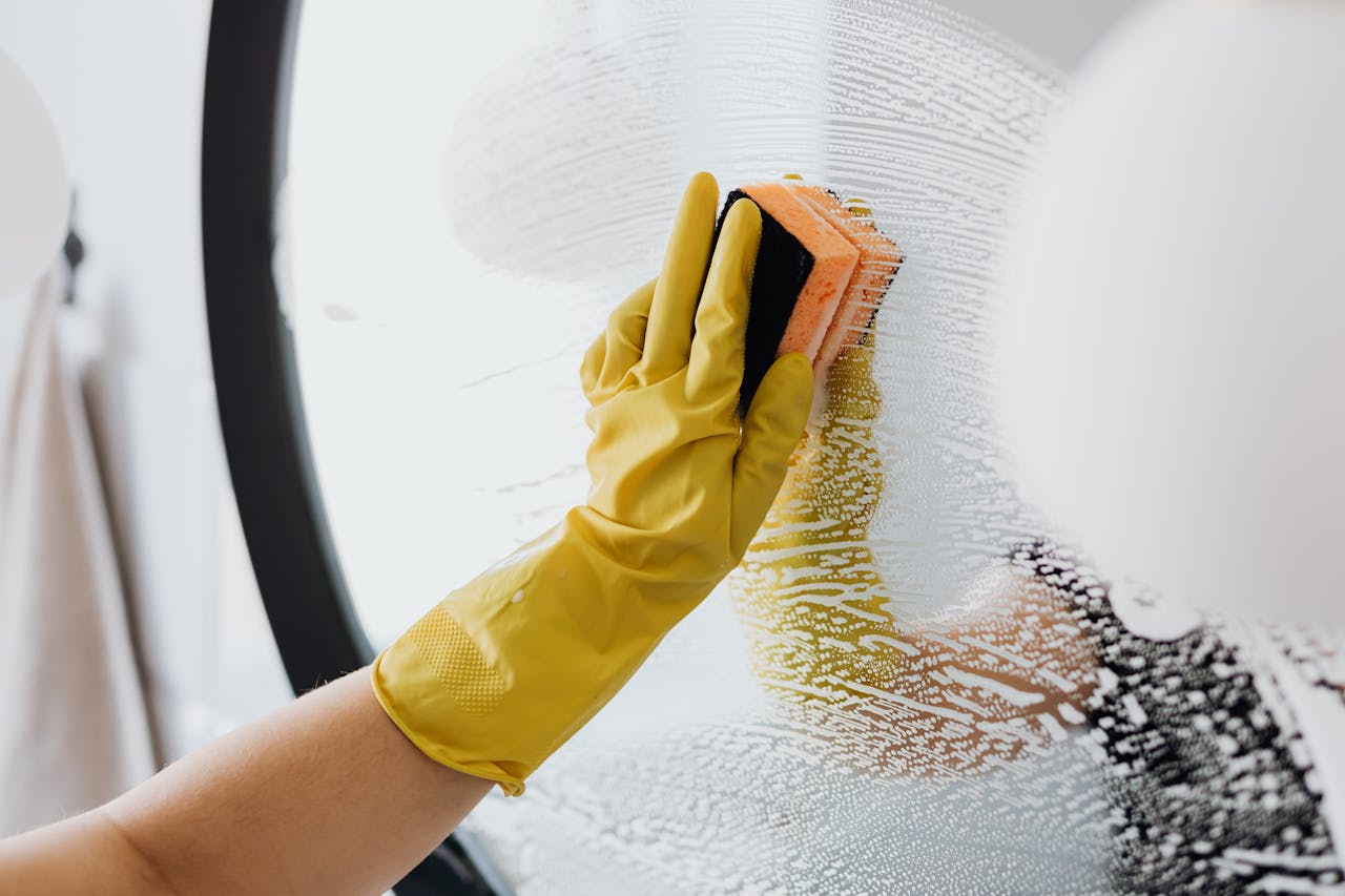 team-01 Anonymous person in yellow rubber gloves using simple sponge for cleaning mirror in bathroom